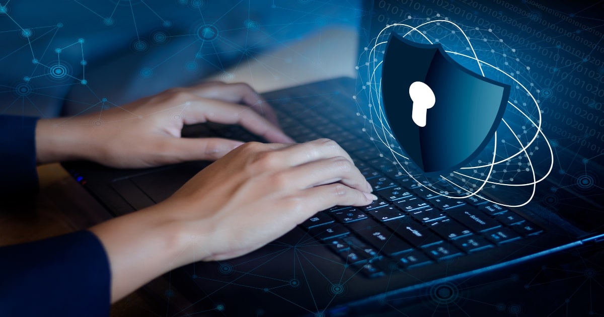 Hands typing on a laptop keyboard with a digital padlock shield icon, symbolising cybersecurity and data protection.